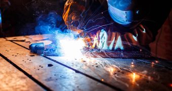 Worker cutting metal with plasma equipment on plant.